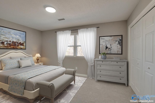 carpeted bedroom with a textured ceiling and a closet