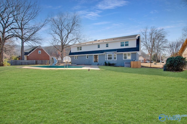 back of house with a fenced in pool, a patio, and a lawn