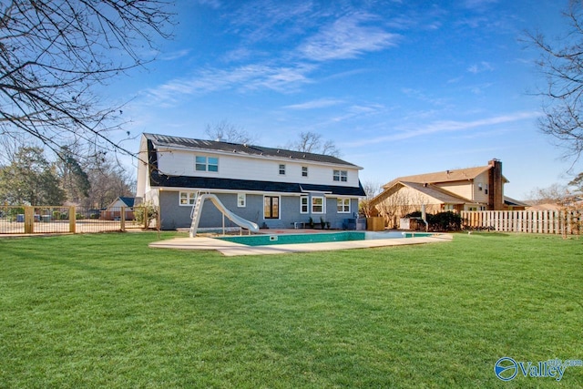 back of property featuring a fenced in pool, a patio area, and a lawn