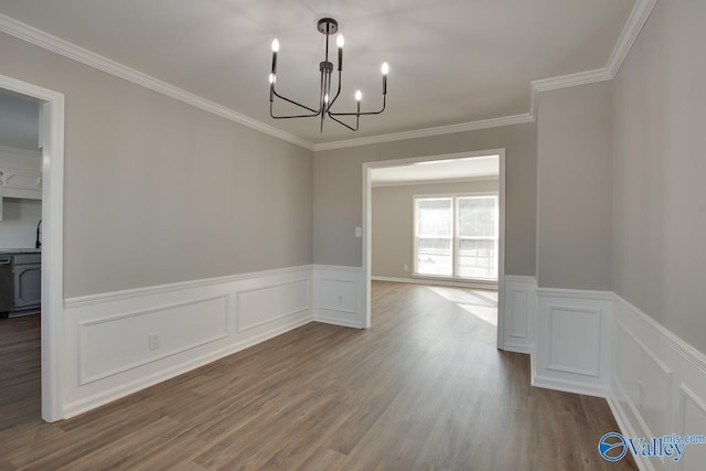 unfurnished dining area featuring crown molding, wood-type flooring, and a notable chandelier