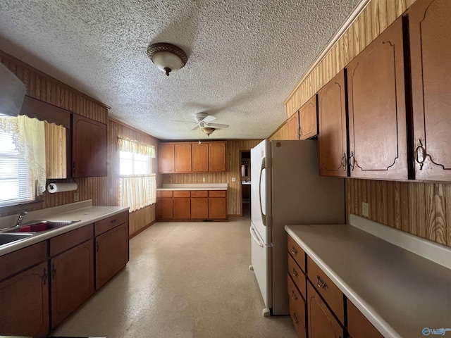 kitchen featuring a sink, ceiling fan, a textured ceiling, and brown cabinets