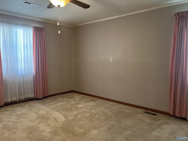 empty room featuring ornamental molding, visible vents, ceiling fan, and carpet floors