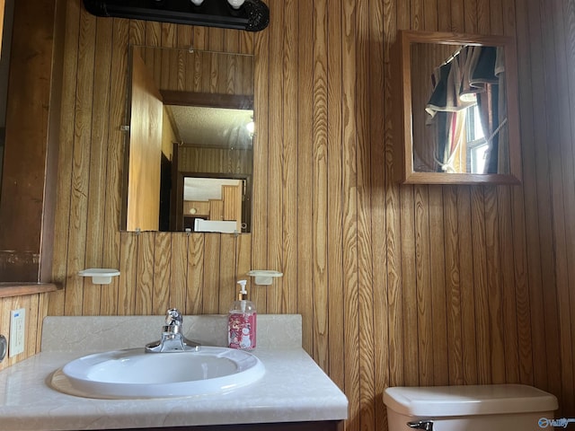 half bath featuring toilet, wooden walls, and vanity