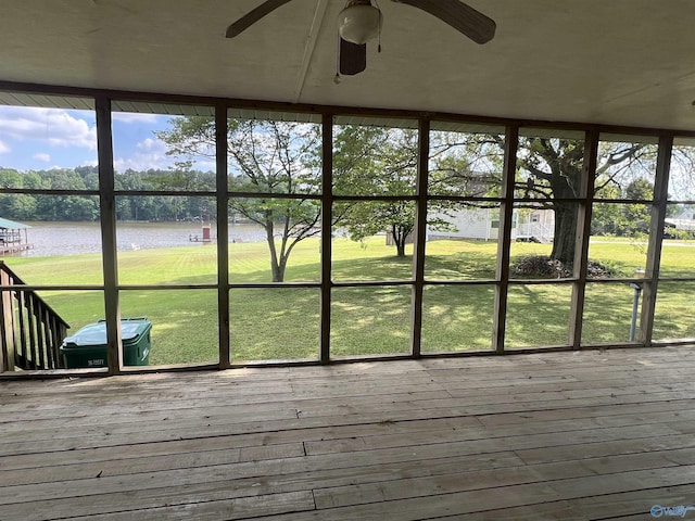 unfurnished sunroom with plenty of natural light, a water view, and ceiling fan