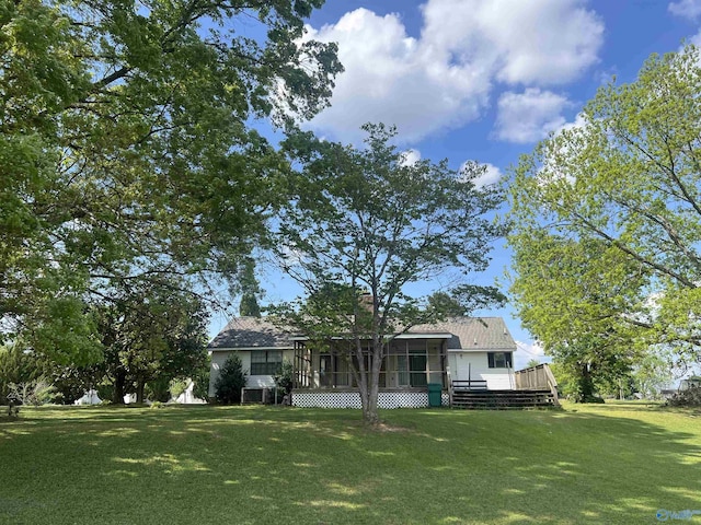 view of front of property with a wooden deck, a sunroom, and a front lawn