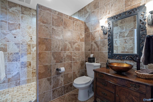 bathroom featuring tile patterned floors, toilet, vanity, and tile walls