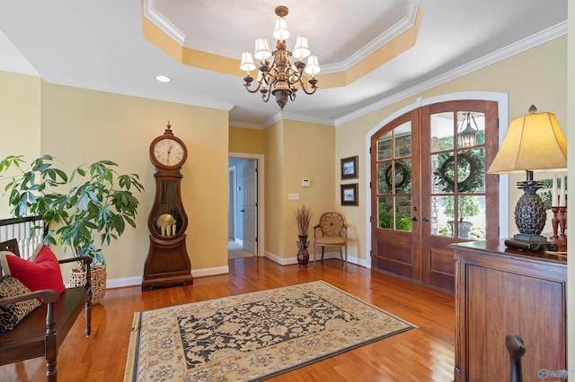 foyer entrance featuring a raised ceiling, crown molding, and hardwood / wood-style floors