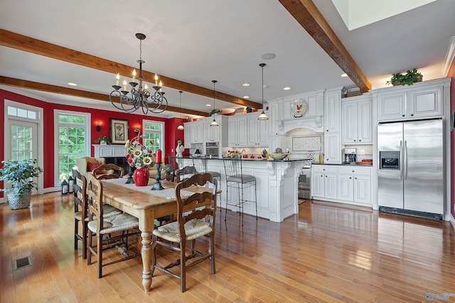 dining space with light wood-type flooring, beam ceiling, and a notable chandelier