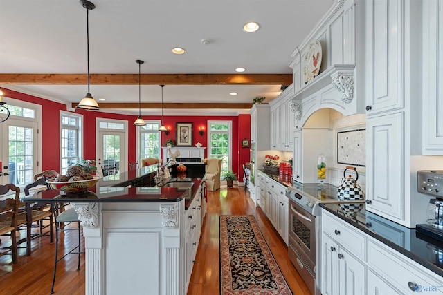 kitchen with a breakfast bar, a center island, light hardwood / wood-style flooring, stainless steel range with electric stovetop, and white cabinetry