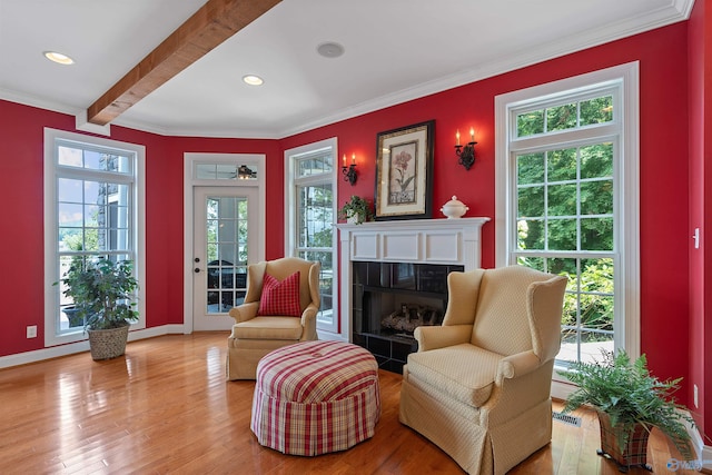 living area with beamed ceiling, ornamental molding, and light wood-type flooring