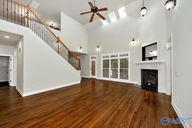 118 Conservancy Dr, Madison, AL 35758 - unfurnished living room with high vaulted ceiling, wood finished floors, a ceiling fan, a fireplace, and stairs