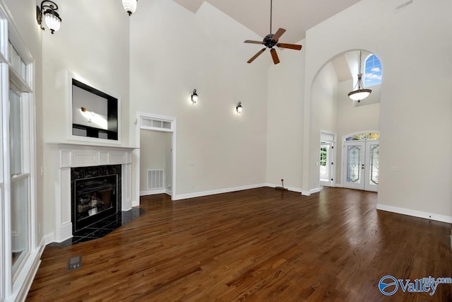 118 Conservancy Dr, Madison, AL 35758 - unfurnished living room with high vaulted ceiling, a ceiling fan, dark wood finished floors, a fireplace, and arched walkways