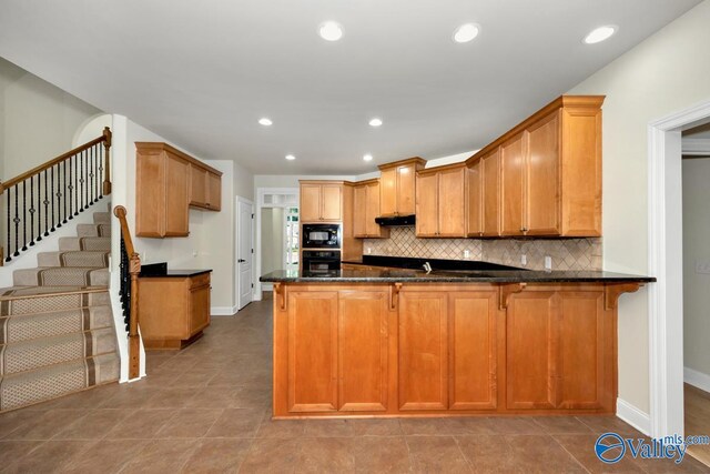 118 Conservancy Dr, Madison, AL 35758 - kitchen with black appliances, a peninsula, dark stone counters, backsplash, and under cabinet range hood