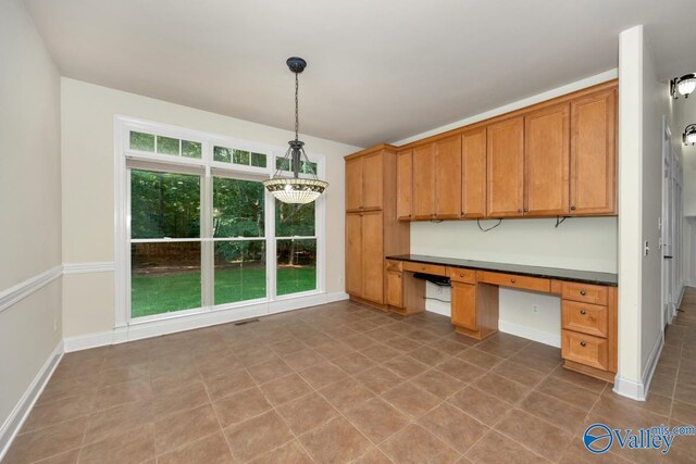 118 Conservancy Dr, Madison, AL 35758 - kitchen with built in desk, dark countertops, pendant lighting, brown cabinets, and tile patterned floors
