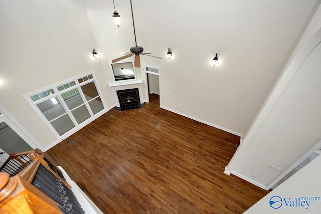 118 Conservancy Dr, Madison, AL 35758 - unfurnished living room featuring a fireplace, wood finished floors, a ceiling fan, and a towering ceiling