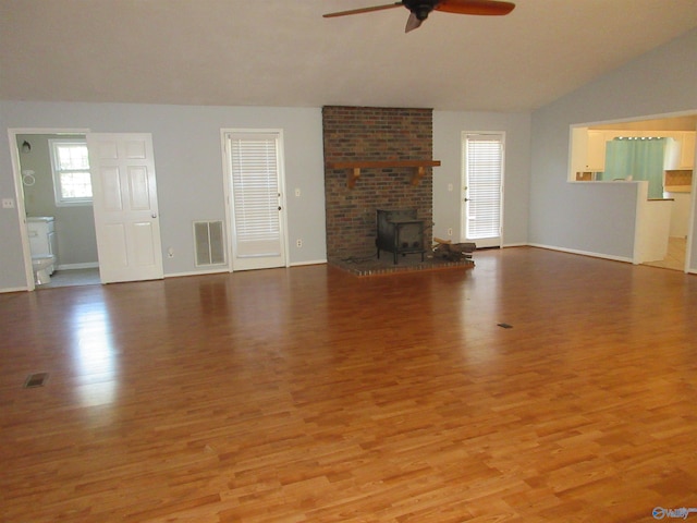 109 Colonial Dr, Scottsboro, AL 35768 - unfurnished living room featuring visible vents, a ceiling fan, wood finished floors, a wood stove, and vaulted ceiling