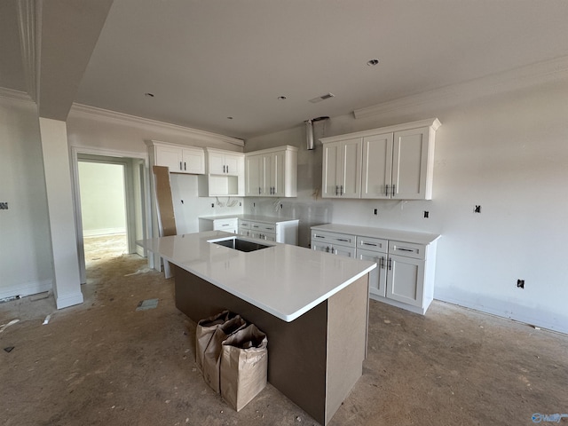 kitchen featuring a sink, white cabinets, visible vents, a kitchen island, and ornamental molding