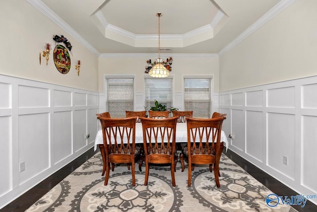 dining space featuring ornamental molding, a tray ceiling, and dark hardwood / wood-style flooring