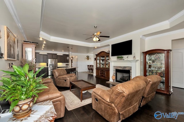 living room with ceiling fan, crown molding, a fireplace, and dark hardwood / wood-style flooring