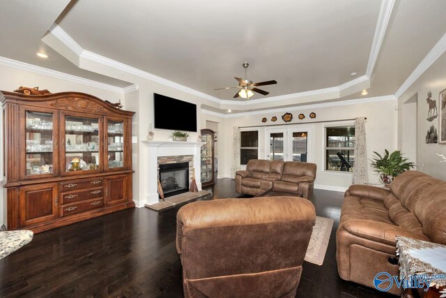 living room with dark hardwood / wood-style floors, a fireplace, a tray ceiling, and ceiling fan