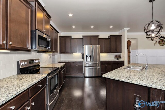 kitchen featuring appliances with stainless steel finishes, pendant lighting, sink, dark brown cabinetry, and light stone countertops