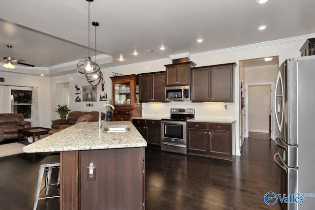 kitchen featuring pendant lighting, sink, appliances with stainless steel finishes, a kitchen bar, and a center island with sink