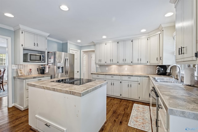 kitchen with appliances with stainless steel finishes, a sink, crown molding, tasteful backsplash, and a center island
