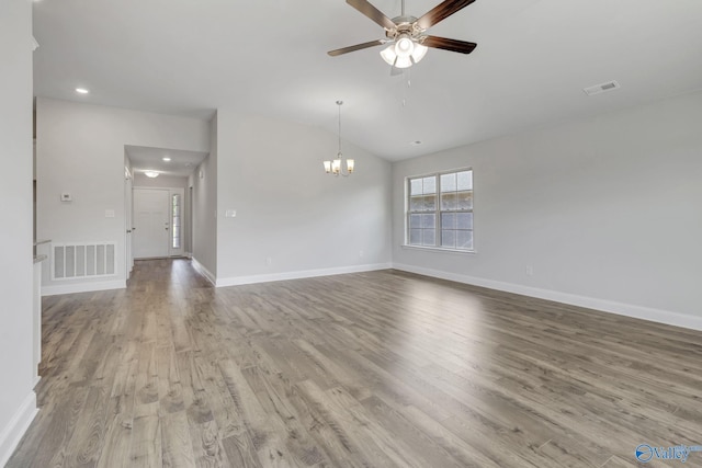 spare room with ceiling fan with notable chandelier, light hardwood / wood-style flooring, and vaulted ceiling