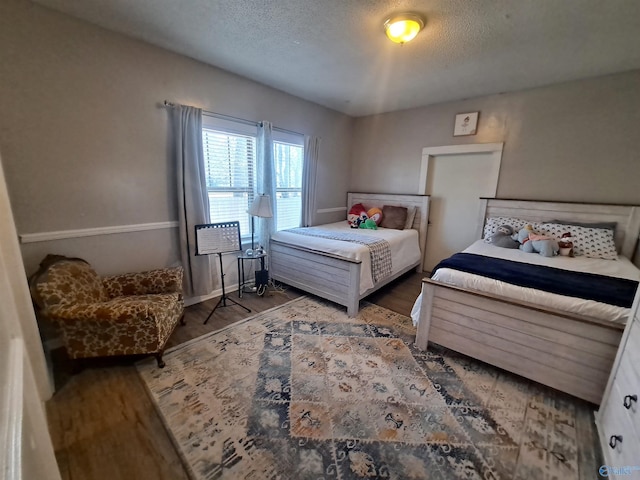 bedroom with a textured ceiling and wood finished floors