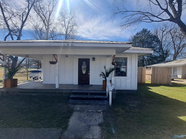 view of front facade with metal roof, board and batten siding, and a front lawn