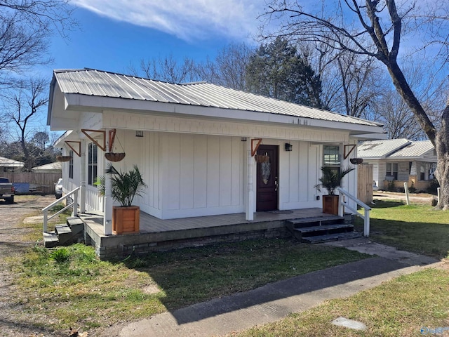 bungalow featuring a porch, metal roof, a front lawn, and board and batten siding