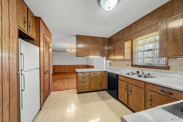 kitchen featuring sink, black dishwasher, white refrigerator, a textured ceiling, and decorative light fixtures