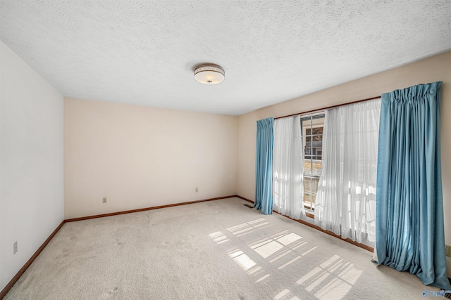 spare room featuring light carpet and a textured ceiling