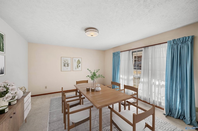 dining area featuring light colored carpet and a textured ceiling