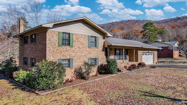 tri-level home with a mountain view, a porch, and a garage