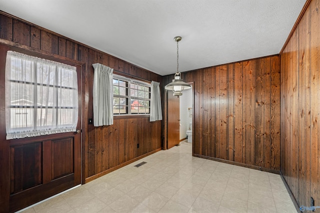 unfurnished dining area featuring wooden walls