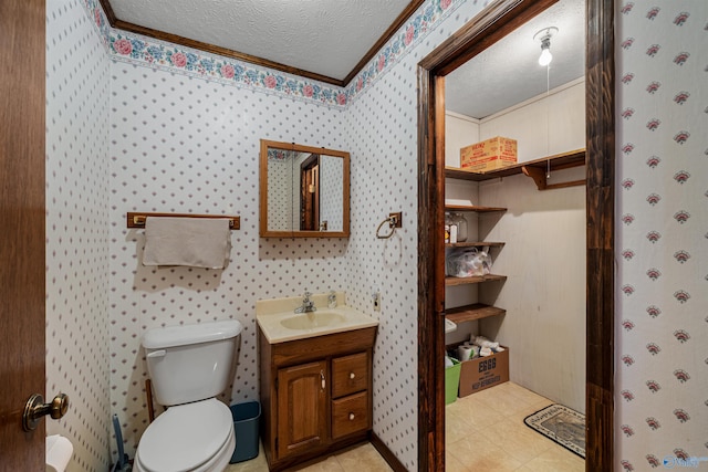 bathroom featuring tile patterned flooring, crown molding, a textured ceiling, toilet, and vanity