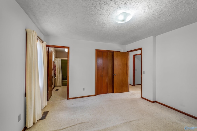 unfurnished bedroom with light carpet, a textured ceiling, and a closet