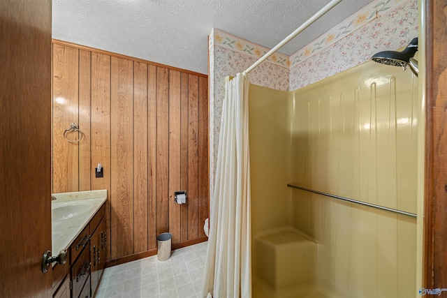 bathroom with curtained shower, wooden walls, vanity, and a textured ceiling