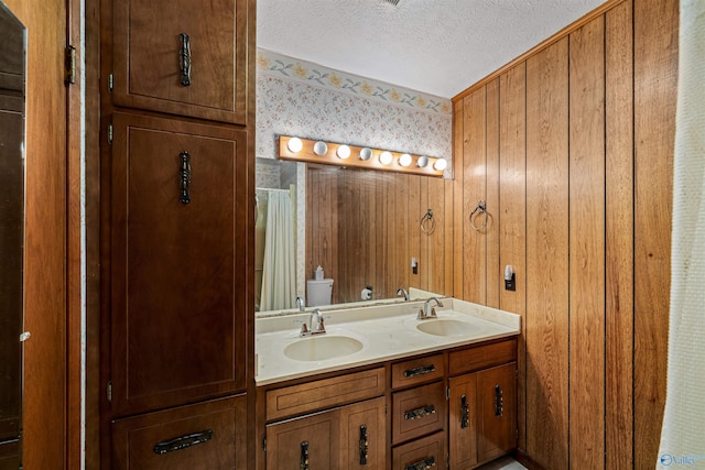 bathroom featuring wood walls, vanity, a textured ceiling, and toilet