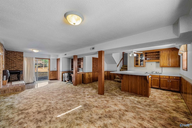 kitchen featuring wood walls, light colored carpet, a textured ceiling, and a kitchen island