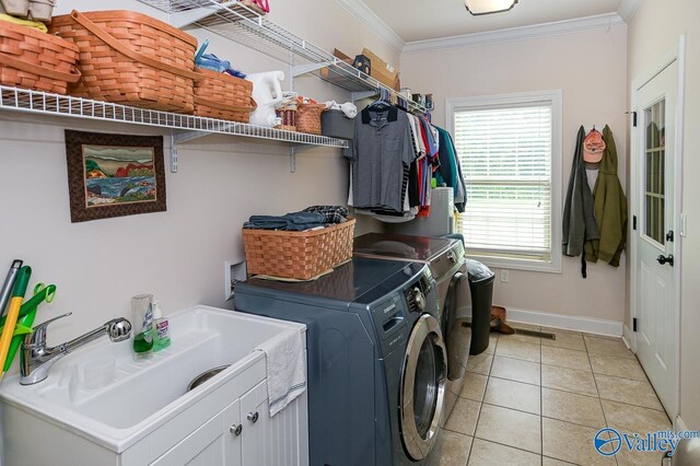 clothes washing area featuring sink, cabinets, light tile patterned floors, ornamental molding, and independent washer and dryer