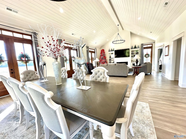 dining room with french doors, lofted ceiling with beams, light wood-type flooring, and wood ceiling