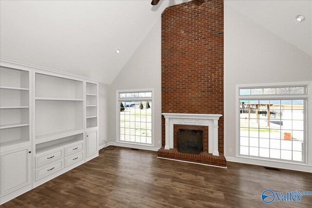 unfurnished living room with a fireplace, dark wood-type flooring, and high vaulted ceiling