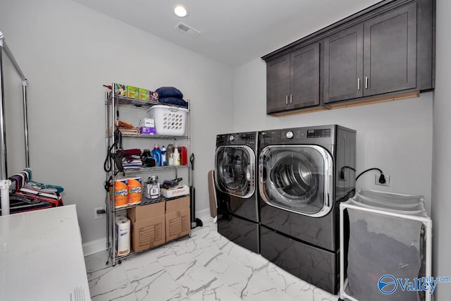 clothes washing area featuring washing machine and dryer and cabinets