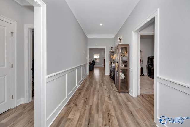 hallway with light wood-type flooring and crown molding