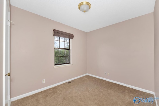 spare room featuring carpet floors, baseboards, and visible vents