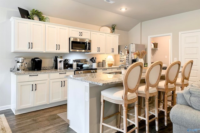 kitchen featuring a kitchen island with sink, white cabinets, appliances with stainless steel finishes, dark hardwood / wood-style flooring, and light stone countertops