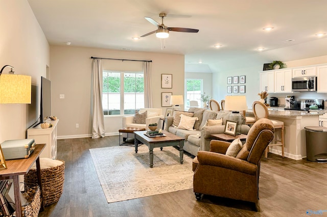 living room featuring vaulted ceiling, ceiling fan, and dark wood-type flooring