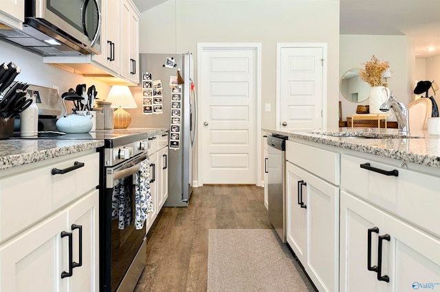 kitchen featuring light stone counters, sink, white cabinetry, appliances with stainless steel finishes, and hardwood / wood-style floors